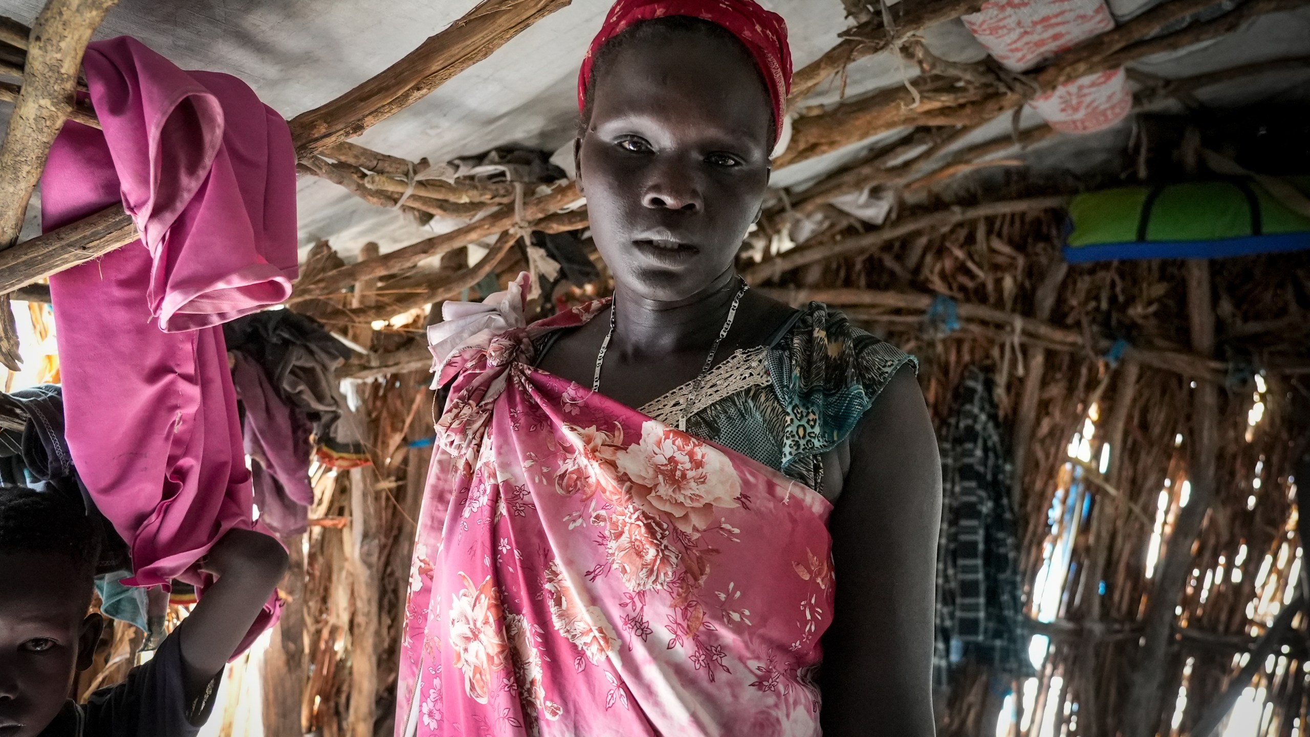 Nyarok Gach, who fled Sudan after fighting erupted and returned to her home village in South Sudan earlier this month, stands in a house that she shares with her eight children and other families, at Wunlueth village in Canal-Pigi county, South Sudan Thursday, May 4, 2023. More than 40,000 people, mostly South Sudanese, have crossed the border into South Sudan since Sudan erupted in conflict nearly one month ago, yet many are returning to areas unable to support them and still riddled by fighting. (AP Photo/Sam Mednick)