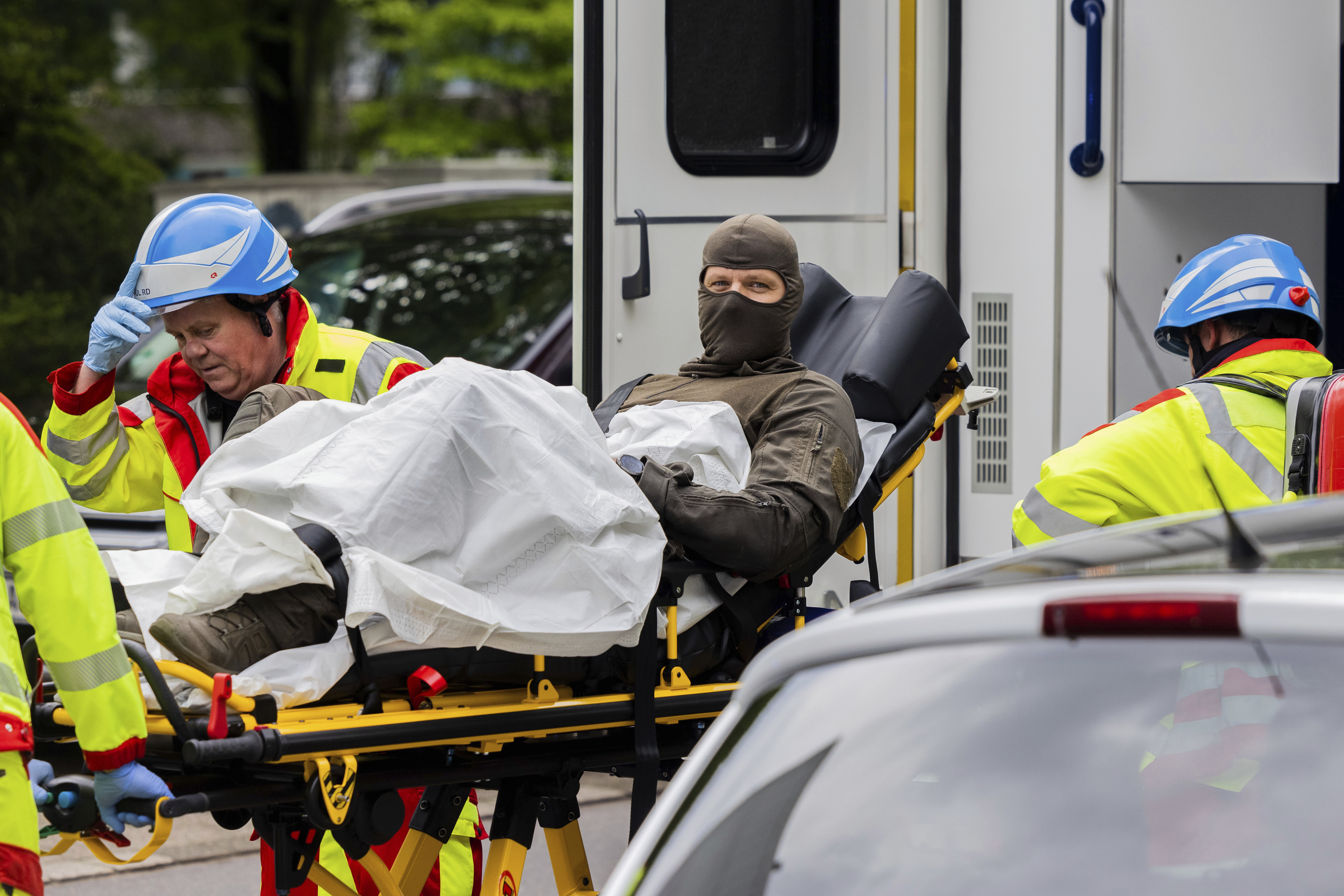 An injured police officer is taken to an ambulance in front of a high-rise building in Ratingen, Germany, Thursday May 11, 2023. A senior security official says at least a dozen people have been injured in an explosion at a residential building in western Germany. Herbert Reul, Interior Minister of the German state of North Rhine-Westphalia, said that 10 firefighters and two police officers were injured in the blast at a high-rise building in the town of Ratingen. (Rolf Vennenbernd/dpa via AP)