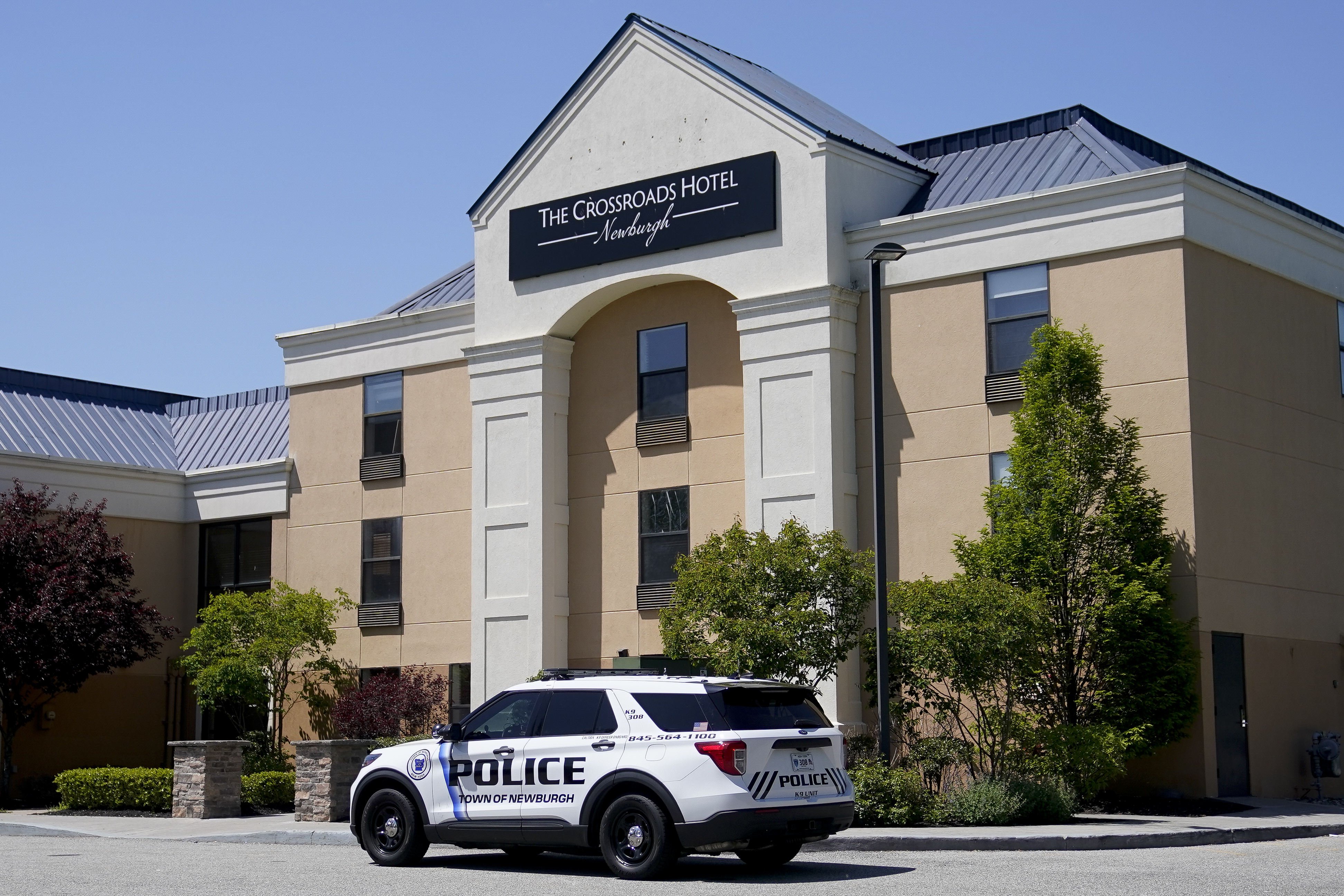 A Town of Newburgh police vehicle is parked outside The Crossroads Hotel where two busloads of migrants arrived hours earlier, Thursday, May 11, 2023, in Newburgh, N.Y. New York City Mayor Eric Adams touched off a furor north of the city by announcing last week that the city would temporarily send north up to 300 single, adult men to two hotels in suburban Rockland County and neighboring Orange County. (AP Photo/John Minchillo)