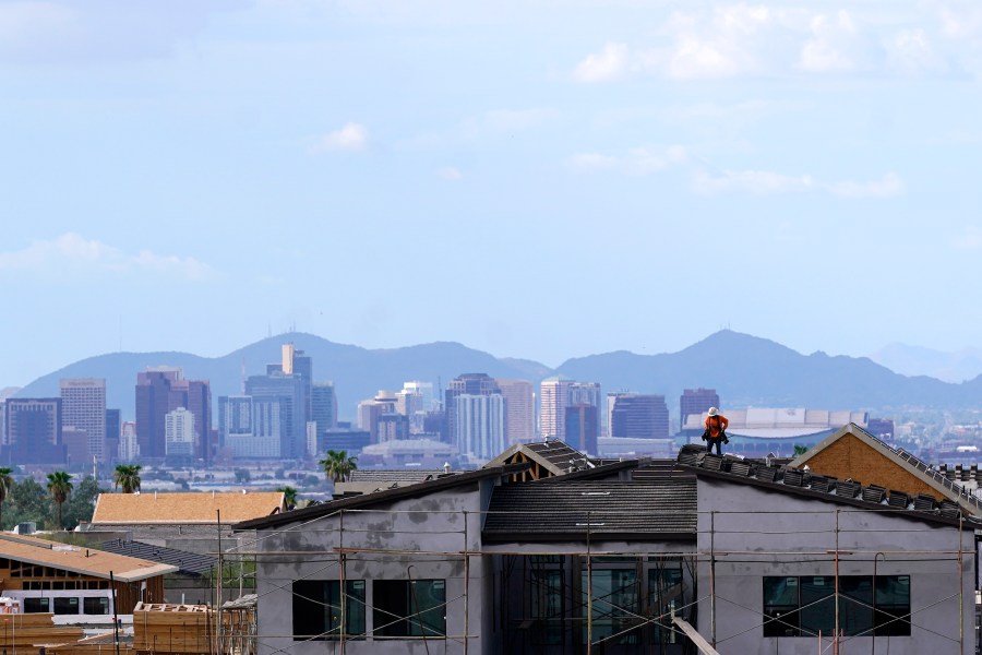 FILE - In this Aug. 12, 2021, file photo with the downtown skyline in the background, a roofer works on a new home being built in a new housing development as expansive urban sprawl continues in Phoenix. Some of the largest U.S. cities challenging their 2020 census numbers aren't getting the results they hoped for from the U.S. Census Bureau. (AP Photo/Ross D. Franklin, File)