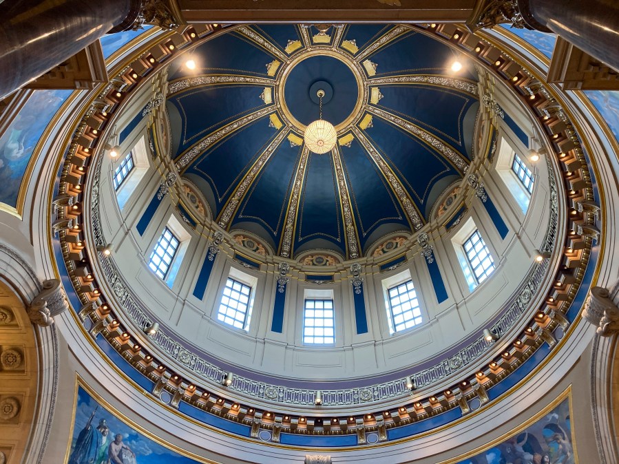 The "electrolier" is lit in the Minnesota State Capitol dome in St. Paul, Minn., Thursday, May 11, 2023, to mark Statehood Day, Minnesota's 165th birthday. The electrolier," an old term for "electric chandelier," is over 100 years old, dating from when electricity was new. It measures 6 feet in diameter, contains 92 light bulbs and hangs over 140 feet above the floor in the Capitol Rotunda. It's lit only on special occasions, such as the annual Statehood Day or on the first days of legislative sessions. (AP Photo/Steve Karnowski)