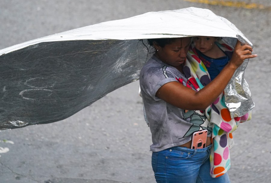 A Venezuelan migrant uses an emergency blanket as cover from the rain, near the banks of the Rio Grande in Matamoros, Mexico, Saturday, May 13, 2023. As the U.S. ended its pandemic-era immigration restrictions, migrants are adapting to new asylum rules and legal pathways meant to discourage illegal crossings. (AP Photo/Fernando Llano)