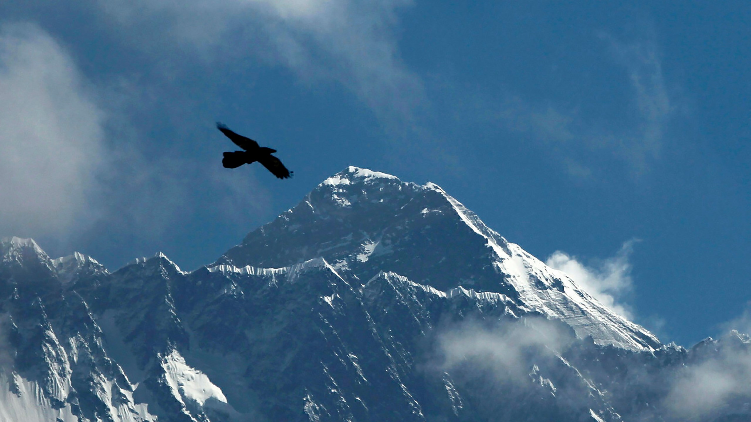 FILE - A bird flies with Mount Everest seen in the background from Namche Bajar, Solukhumbu district, Nepal, May 27, 2019. A Sherpa guide scaled Mount Everest on Sunday for the 26th time, matching the record set by a fellow Nepalese guide for the most ascents of the world’s highest peak. (AP Photo/Niranjan Shrestha, File)