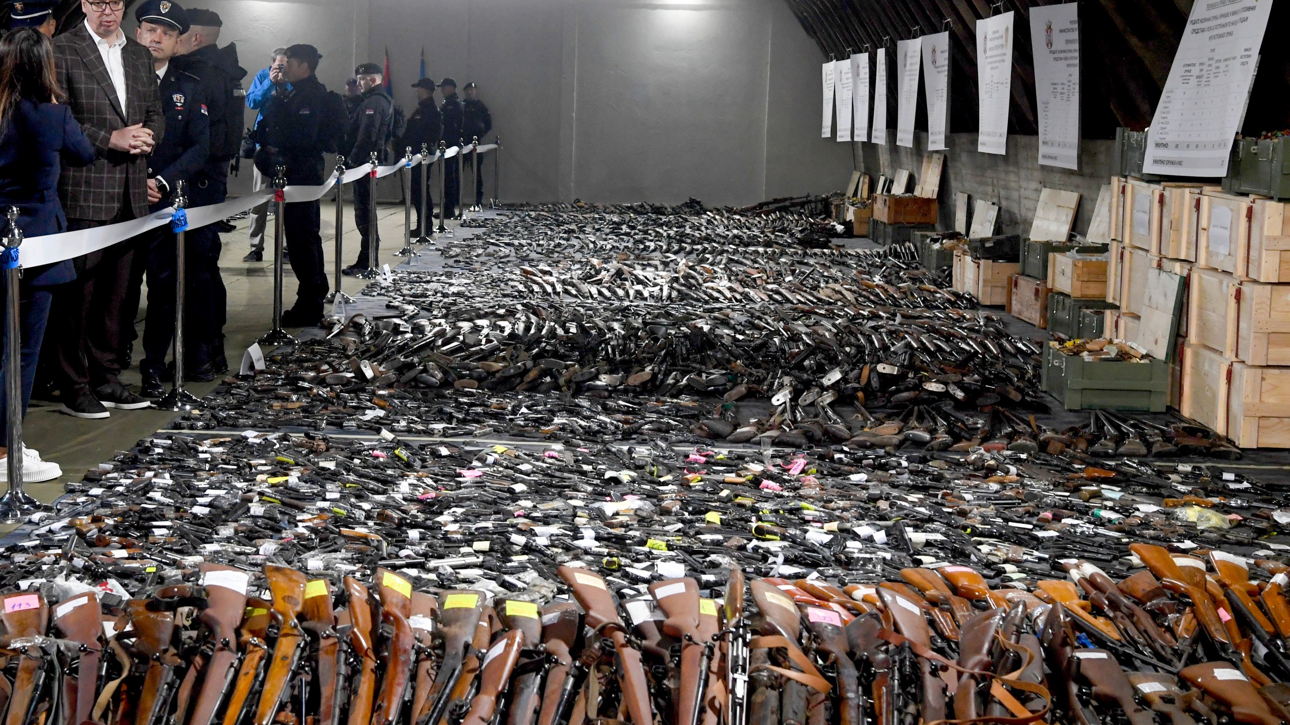 In this photo provided by the Serbian Presidential Press Service, Serbian President Aleksandar Vucic, left, inspects weapons collected as part of an amnesty near the city of Smederevo, Serbia, Sunday, May 14, 2023. Serbian authorities on Sunday displayed some of around 13,500 weapons they say have been collected since last week's mass shootings, including automatic weapons, hand bombs and anti-tank grenades. (Serbian Presidential Press Service via AP)