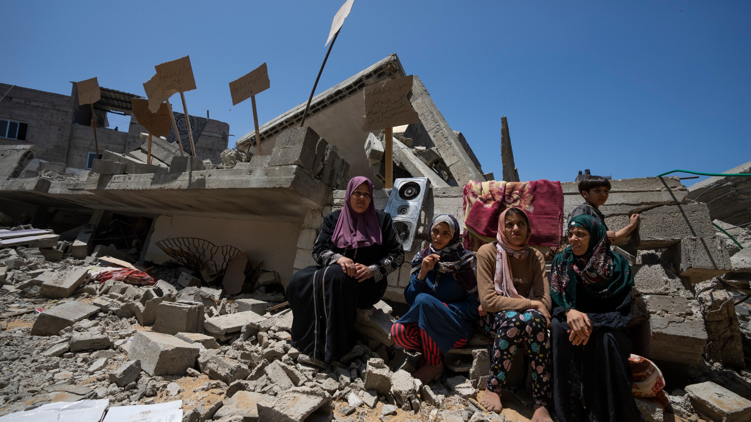 Members of the Nabhan family, including three sisters with special needs, sit in front of the ruins of their home, which was destroyed in an Israeli airstrike in Jabaliya, northern Gaza Strip, Sunday, May 14, 2023. The airstrike left 42 members of the extended family homeless. It also left four children with special needs without their wheelchairs, crutches and medical equipment needed to move about. Israel says the building was used as a command center by the Islamic Jihad militant group. The two sides reached a cease-fire Saturday to end five days of fighting. (AP Photo/Fatima Shbair)