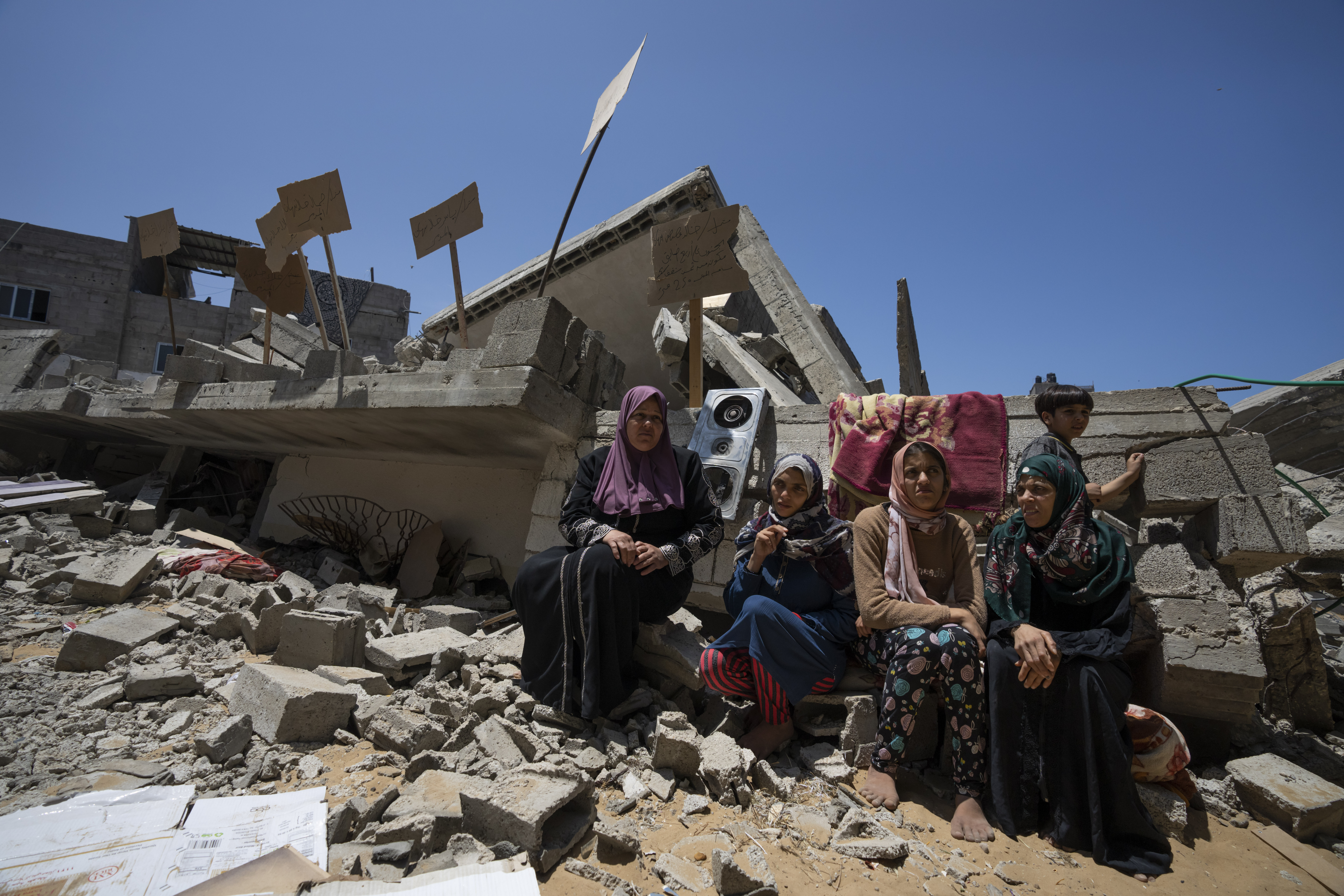 Members of the Nabhan family, including three sisters with special needs, sit in front of the ruins of their home, which was destroyed in an Israeli airstrike in Jabaliya, northern Gaza Strip, Sunday, May 14, 2023. The airstrike left 42 members of the extended family homeless. It also left four children with special needs without their wheelchairs, crutches and medical equipment needed to move about. Israel says the building was used as a command center by the Islamic Jihad militant group. The two sides reached a cease-fire Saturday to end five days of fighting. (AP Photo/Fatima Shbair)